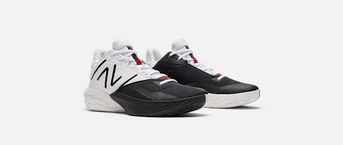 Side view of white, black, and red New Balance basketball shoes.